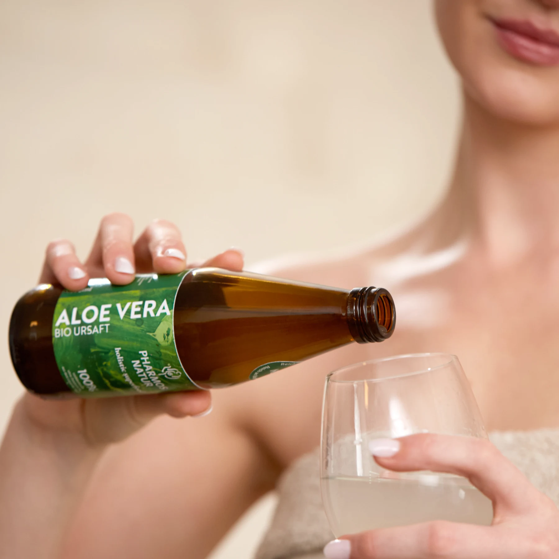 Frau schenkt sich Aloe Vera Bio Ursaft von Pharmos Natur in ein Glas ein