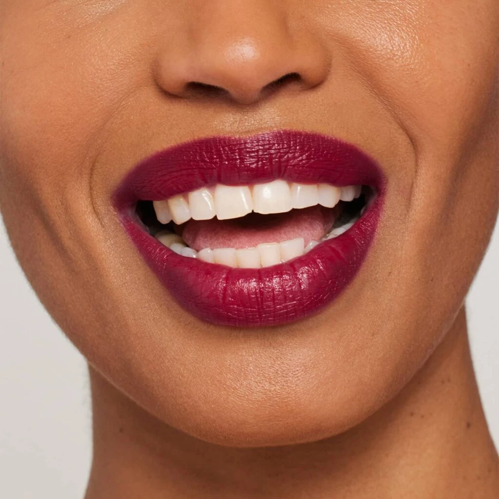 Frau mit dunklem Hautton, auf den Lippen den ColorLuxe Lippenstift von janeiredale in der Farbe Passionfruit - bei Claresco Cosmetic kaufen